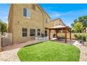 This backyard features a grassy area, a charming white picket fence, and a cozy gazebo with outdoor seating at 8015 Maple Park St, Las Vegas, NV 89131