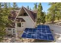 A-frame home with solar panels and a bay window, set amidst tall pine trees at 5230 Whispering Robin Ln, Mount Charleston, NV 89124