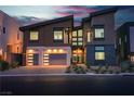 Modern home exterior showcasing garage doors with horizontal windows and dramatic evening lighting at 5364 Succulent Rose Dr, Las Vegas, NV 89135