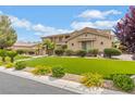 Beautiful home exterior with lush green lawn, landscaped with bushes and flowers at 7001 Via Locanda Ave, Las Vegas, NV 89131