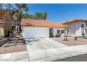 Inviting single-story home features a red tile roof, desert landscaping, and a two car garage at 8640 Trafalgar Dr, Las Vegas, NV 89117