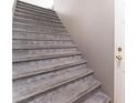Carpeted staircase with gray steps leading upwards next to a light gray wall and a closed door at 9303 Gilcrease Ave # 1013, Las Vegas, NV 89149