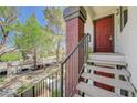 Welcoming condo entrance via stairs, featuring neutral tones, a red door, and a view of mature landscaping at 950 Seven Hills Dr # 1921, Henderson, NV 89052