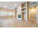 Spacious living room with tile flooring, recessed lighting, a cozy fireplace, and built-in shelves for decor at 11082 Sospel Pl, Las Vegas, NV 89141
