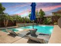 Outdoor pool and hot tub area with lounge chairs, mature trees and a privacy fence under a colorful sky at 2750 Evolutionary Ln, Las Vegas, NV 89138