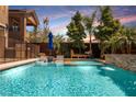 A modern pool with an integrated waterfall feature and surrounded by lounge chairs and manicured landscaping at 2750 Evolutionary Ln, Las Vegas, NV 89138