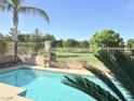 Inviting pool with palm trees and view of green golf course beyond wrought iron fence at 5104 Burr Oak Dr, Las Vegas, NV 89130