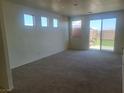 Open-plan living room featuring neutral carpet, bright walls, and sliding glass doors to the backyard at 7102 Shimmering Ave, Henderson, NV 89011