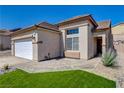 Front exterior featuring desert landscaping, two-car garage, and neutral stucco at 177 Shaded Peak St, Henderson, NV 89012