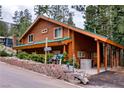 Charming log cabin with a green metal roof, showcasing a covered carport and landscaped front yard with a brick wall at 401 Alpine Way, Las Vegas, NV 89124