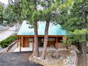 Cozy log cabin with a green metal roof, featuring a convenient carport and ample space for wood storage at 401 Alpine Way, Las Vegas, NV 89124