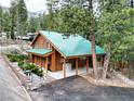 Quaint log cabin with a green metal roof and inviting carport nestled among towering trees and mountain scenery at 401 Alpine Way, Las Vegas, NV 89124
