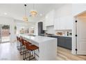 Bright kitchen with waterfall island, stylish pendant lighting, stainless appliances and breakfast bar seating at 4176 Demoline Cir, Las Vegas, NV 89141