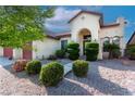 Front exterior of home featuring stucco siding, three-car garage, arched entry, and manicured landscaping at 5016 Wayfaring Tree Ave, Las Vegas, NV 89131