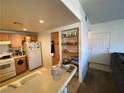 Functional kitchen space with wood cabinets, white appliances and breakfast bar with pantry shelves at 9580 W Reno Ave # 283, Las Vegas, NV 89148