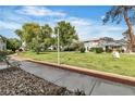 Landscaped community exterior with green grass and mature trees on a sunny day at 163 Greenbriar Townhouse Way, Las Vegas, NV 89121