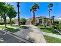 Beautiful single-story home with a circular driveway, mature palm trees, and green lawns at 2345 Villandry Ct, Henderson, NV 89074