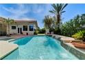 Sparkling pool with waterfall feature and lush tropical landscaping creating a backyard paradise at 2345 Villandry Ct, Henderson, NV 89074