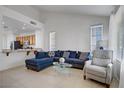 Bright living room with large windows, a plush blue sectional, and neutral tile flooring at 2851 Glistening Grove Ave, Henderson, NV 89052