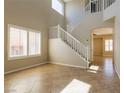 Bright living room with high ceilings, tiled floors, and a staircase with white railings at 3615 Dutchmans Vine Ct, North Las Vegas, NV 89081