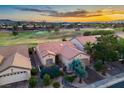 Aerial view of a home with red tile roof and manicured landscaping in golf course community at sunset at 499 Eagle Vista Dr, Henderson, NV 89012