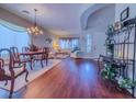 Open-concept living and dining area with hardwood floors, elegant chandelier, and bright natural light at 7225 Millerbird St, North Las Vegas, NV 89084