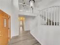 Bright foyer with hardwood flooring, white staircase, and a modern light fixture, offering a welcoming entrance at 8632 Skyward Ct, Las Vegas, NV 89145