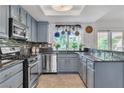 Bright kitchen features blue cabinets, granite countertops, stainless steel appliances, and a view from the large window at 1803 Candle Bright Dr, Henderson, NV 89074