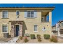 Exterior view of a townhome with stone accents, small balcony, and well-maintained landscaping at 8490 Classique Ave # 101, Las Vegas, NV 89178
