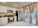 Bright kitchen featuring white cabinets, stainless steel appliances, and sliding glass doors to the patio at 3322 Dragon Fly St, North Las Vegas, NV 89032