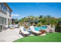 Resort style pool, waterfall, and lounge chairs with an outdoor seating area surrounded by lush landscaping at 7538 Mustang St, Las Vegas, NV 89131