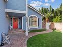 Inviting front porch with a red door, brick pathway, well-maintained lawn, and lovely landscaping at 9436 Darwell Dr, Las Vegas, NV 89117