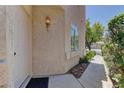 Close-up of the stucco house exterior, showcasing an elegant entrance with stylish lighting fixture and manicured garden at 108 Broken Rock Dr, Henderson, NV 89074