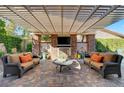 Inviting outdoor living space with stone fireplace, TV, comfortable seating, and elegant brick patio at 748 Puerto Real Ct, Las Vegas, NV 89138