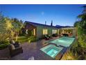 Beautiful backyard pool and spa area with covered patio and elegant landscaping at night at 748 Puerto Real Ct, Las Vegas, NV 89138