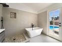 Modern bathroom boasts a freestanding tub, separate walk-in shower and stylish fixtures with a view of the backyard pool at 8000 Vista Twilight Dr, Las Vegas, NV 89123