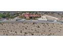 A vast desert landscape leads to an expansive estate with a red tile roof and a gated entrance at 10280 W La Mancha Ave, Las Vegas, NV 89149
