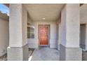 Inviting covered front porch with decorative columns and a bright orange front door at 1225 Stonesthrow Cir, North Las Vegas, NV 89031