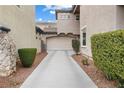View of a long driveway leading to an attached two-car garage, framed by lush landscaping at 2231 Desert Prairie St, Las Vegas, NV 89135