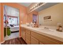 Well-lit bathroom featuring double sinks and wood cabinetry, leading to a bedroom at 2725 S Nellis Blvd # 1038, Las Vegas, NV 89121