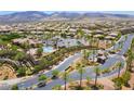 Stunning aerial view of a gated community with palm trees, a pool, and the clubhouse with mountains in the background at 2896 Grande Arch St, Henderson, NV 89044