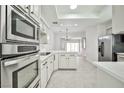 Open kitchen view showcasing white cabinets, stainless steel appliances, and tile flooring at 5316 Fieldstone Rd, Las Vegas, NV 89107