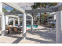Community pool area featuring a BBQ grill and dining table under a shaded pergola near mature trees at 5523 Orchard Ln # 0, Las Vegas, NV 89110