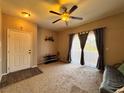 Cozy living room with beige walls, carpet, ceiling fan, and a door at 5750 E Hacienda Ave # 107, Las Vegas, NV 89122