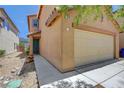 View of the front of the home highlighting the two-car garage and desert landscaping at 7464 Edgecove Ct, Las Vegas, NV 89139