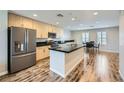 An open layout kitchen with a black countertop island, stainless steel fridge, and wood-look flooring at 9050 W Tropicana Ave # 1015, Las Vegas, NV 89147