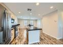 A large kitchen with a black countertop island, stainless steel fridge, and wood-look flooring at 9050 W Tropicana Ave # 1015, Las Vegas, NV 89147