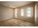 Neutral-toned living room with tile flooring, arched windows, and a view of the front yard at 9312 Poseidon Valley Ave, Las Vegas, NV 89178