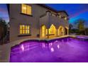 Luxury backyard pool with hot tub, covered patio, arches, and an upstairs balcony at twilight at 12021 La Palmera Ave, Las Vegas, NV 89138