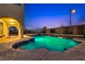 Inviting backyard pool and spa with tiered waterfalls and beautiful landscaping at dusk at 12021 La Palmera Ave, Las Vegas, NV 89138